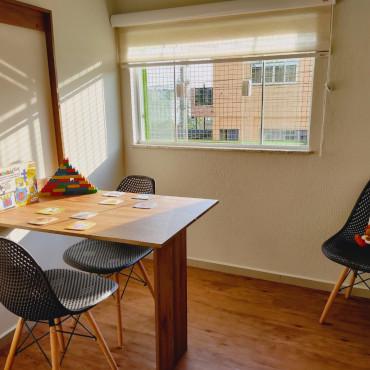Sala iluminada com mesa de atividades e brinquedos